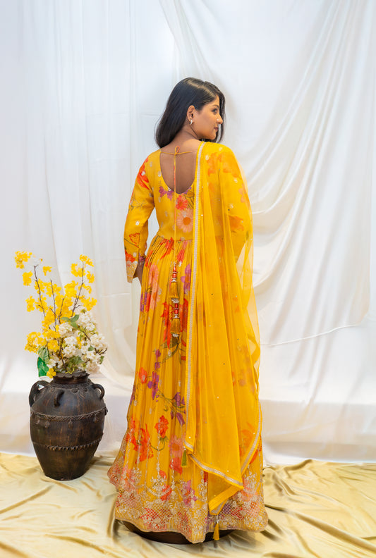 A vibrant yellow traditional gown featuring intricate, colorful floral embroidery