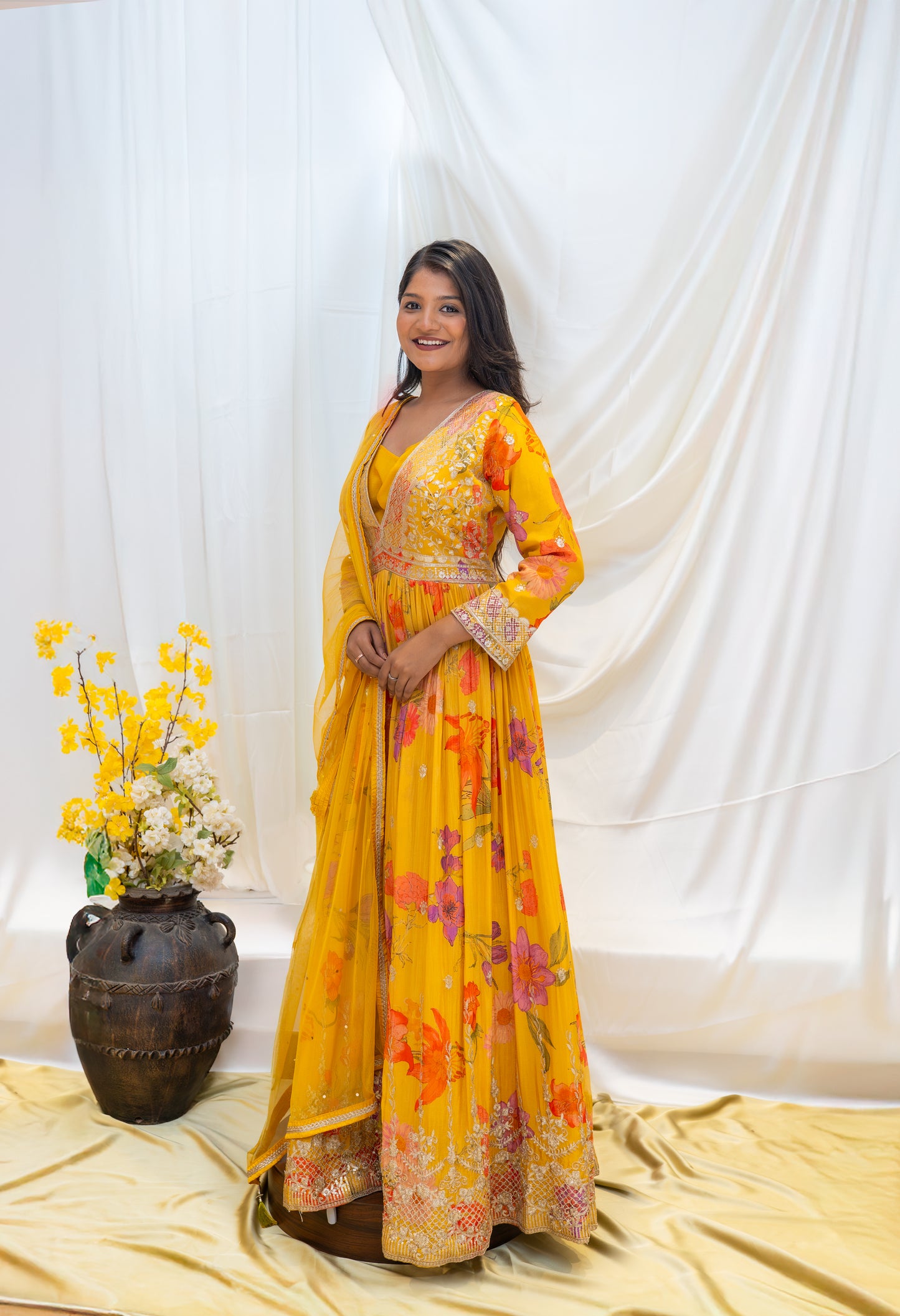 A vibrant yellow traditional gown featuring intricate, colorful floral embroidery