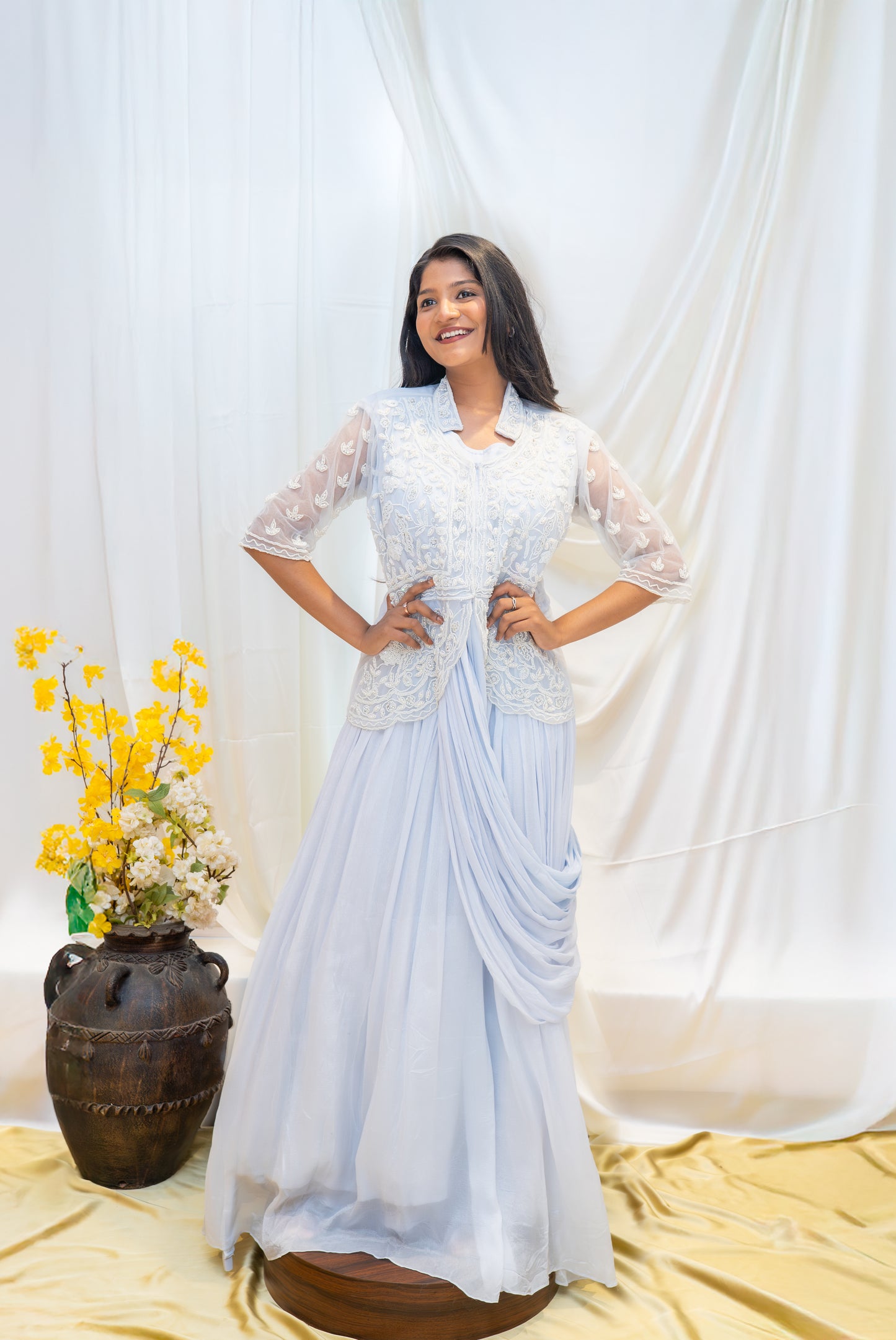 An elegant pastel blue draped gown paired with a delicately embroidered sheer jacket.