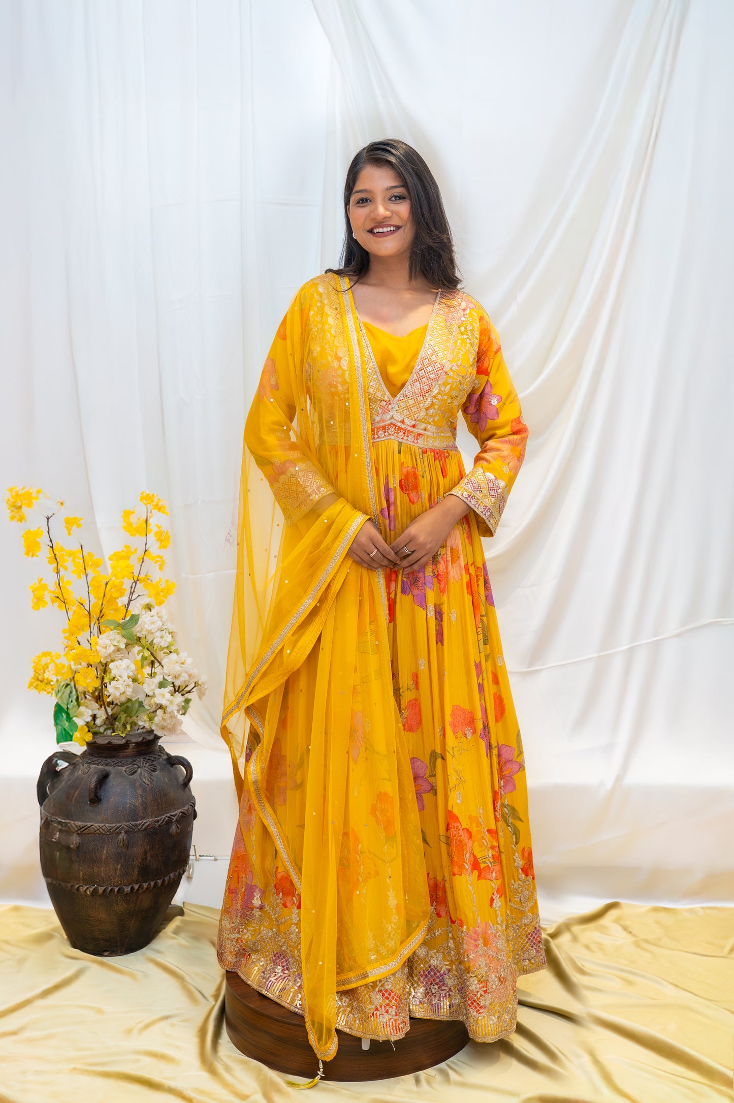 A vibrant yellow traditional gown featuring intricate, colorful floral embroidery