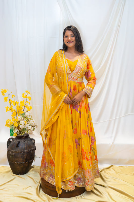 A vibrant yellow traditional gown featuring intricate, colorful floral embroidery
